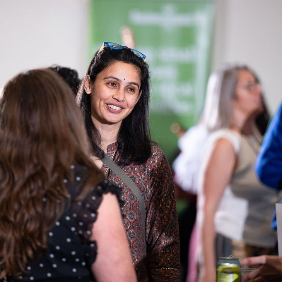 Parvati Patil of Tiny Traditions smiles while talking with another attendee during IMPACT Pitch 2026.
